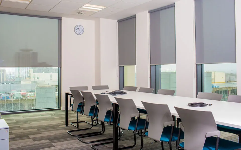 Grey roller blinds fitted in a meeting room